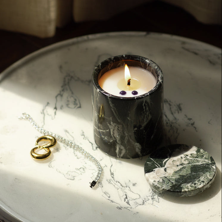 Candle on a marble tray with a bracelet and earrings